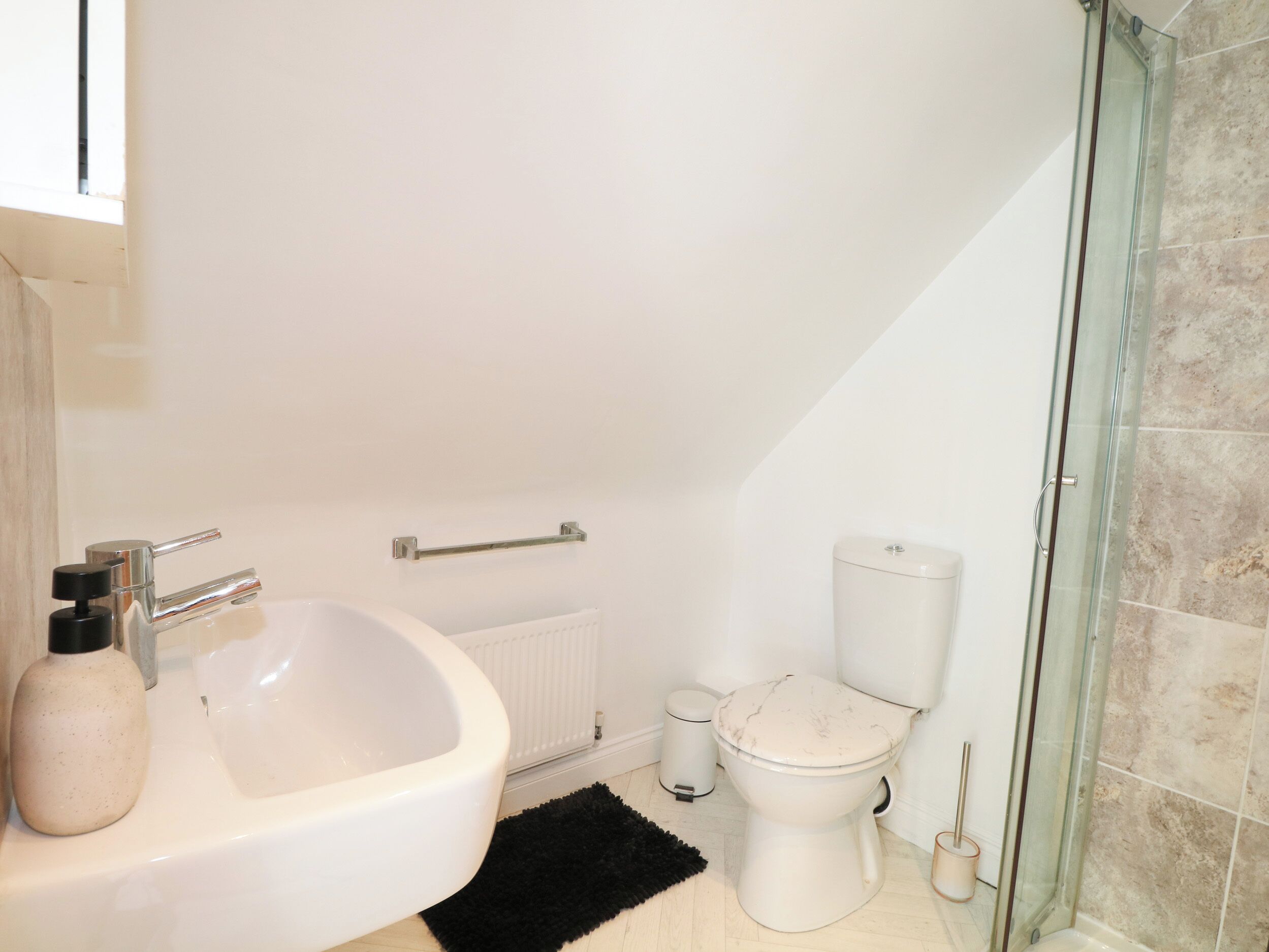 Un baño con lavamanos blanco, inodoro y cabina de ducha de vidrio.