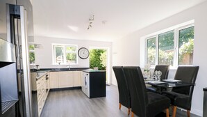 Una cocina moderna con comedor, ventanas amplias y un reloj en la pared.