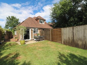 A house with a patio, a wooden fence, and a garden. - Lucerne Cottage (Dorking)