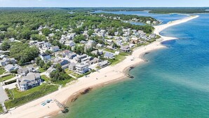 Luchtbeeld van een kustgebied met woonhuizen, een strand en een heldere blauwe oceaan.