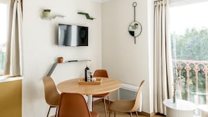 Een moderne eetruimte met een ronde tafel en vier stoelen, een flatscreen televisie aan de muur en een balkon met een hekwerk.