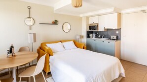 A hotel room with a bed, a dining table, chairs, a kitchen area, and a bathroom. - Studio Standard (Saint-Jean-de-Luz)