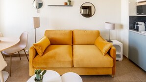 A modern living room with a sofa, a dining table, a lamp, and a kitchen area. - Studio Standard (Saint-Jean-de-Luz)