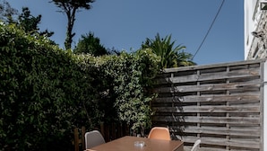Eine Terrasse mit Tisch und Stühlen, ein Holzzaun und ein Gebäude im Hintergrund.