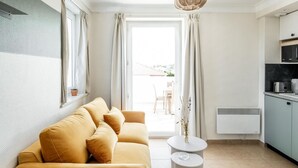 Una sala moderna con un sofá, una mesita redonda y una zona de cocina con armarios y un microondas.