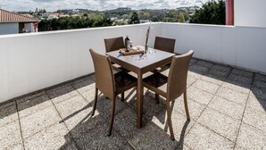Una terraza con mesa y sillas, vista del paisaje y un detalle arquitectónico rojo.