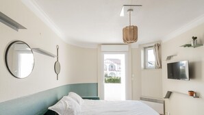Ein Schlafzimmer mit Bett, Nachttisch, Fernseher, Fenster und Tür.