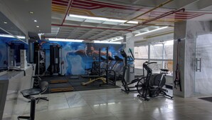 Ein Fitnessraum mit Trainingsgeräten, einem großen Spiegel und einer Wand mit einem dynamischen Bild.