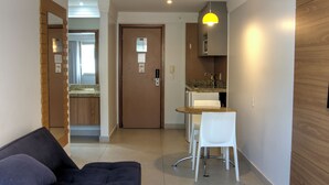 Ein modernes Wohnzimmer mit einer Couch, einem Esstisch mit Stühlen, einer Küchenzeile und einer Wand mit Holzverkleidung.