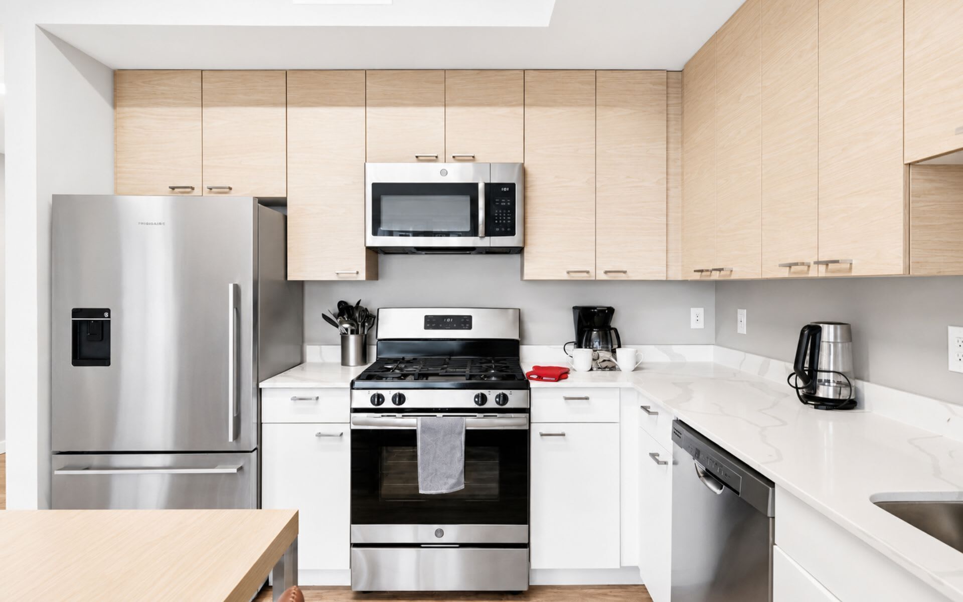 A modern kitchen with stainless steel appliances, wooden cabinets, and a marble countertop.
