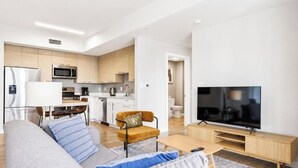 Een moderne woonkamer met een bank, televisie en een eethoek met een tafel en stoelen.