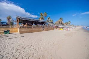 A beachfront restaurant with outdoor seating, palm trees, and a sandy beach. - GuestReady - Marbella vibes with pool (Marbella)