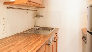 Uma cozinha com armários de madeira, pia de aço inoxidável e forno embutido.
