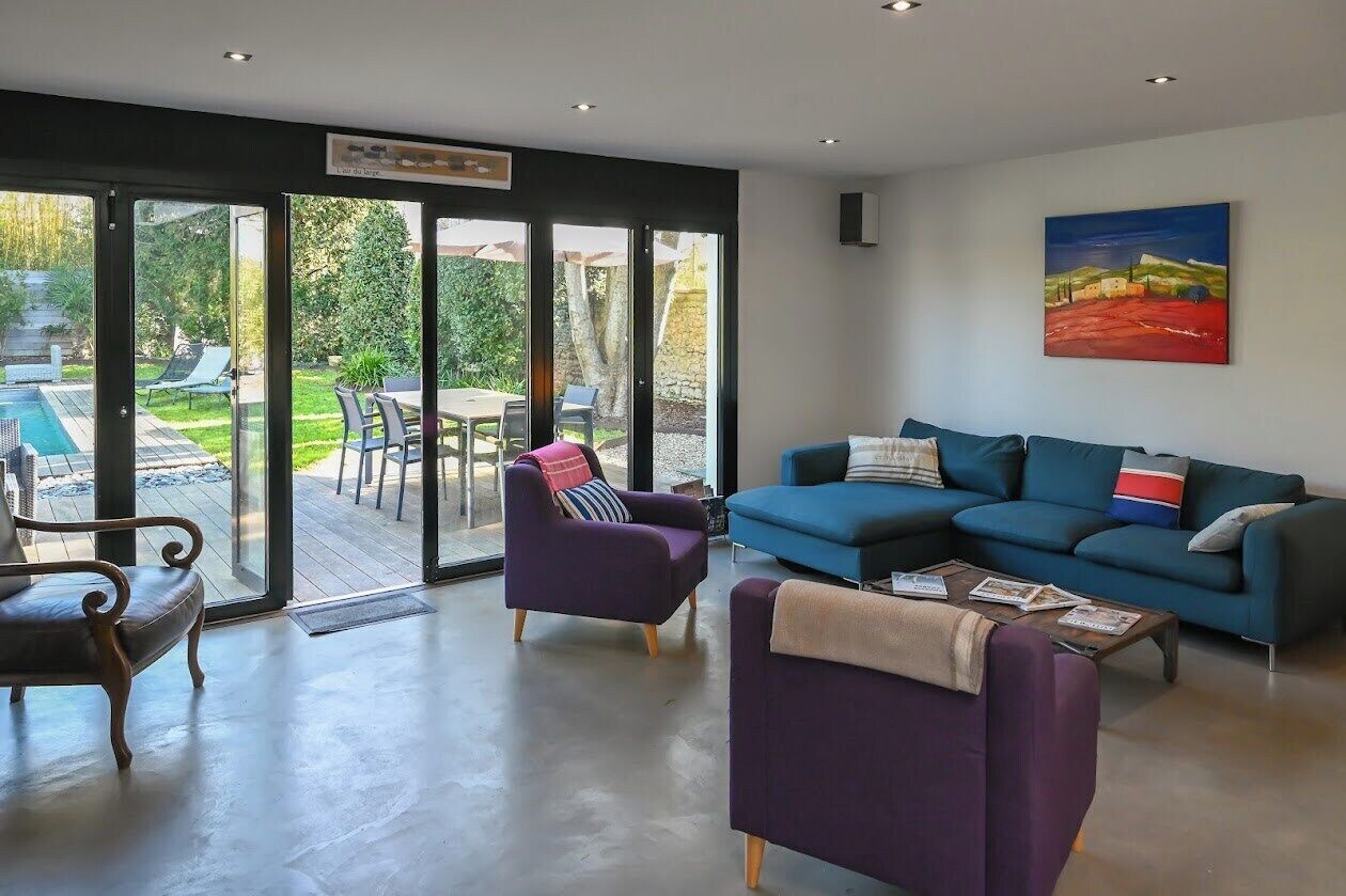 A modern living room with a blue sofa, purple armchairs, and a wooden coffee table.