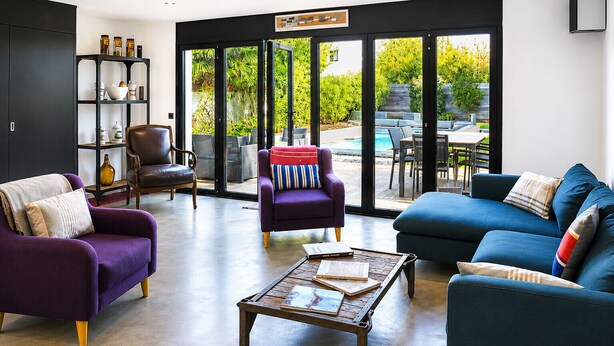 Ein modernes Wohnzimmer mit einer Couch, Sesseln, einem Couchtisch und einem Bücherregal.