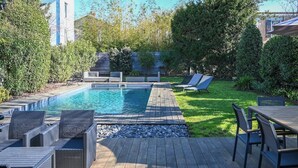 Ein Schwimmbecken mit Liegestühlen und einer Sonnenterrasse.