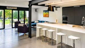 Eine moderne Küche mit Bar, einem Essbereich mit einer Couch und Blick ins Freie.