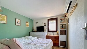 Ein Schlafzimmer mit Bett, Kommode, Fernseher und Wandbildern.
