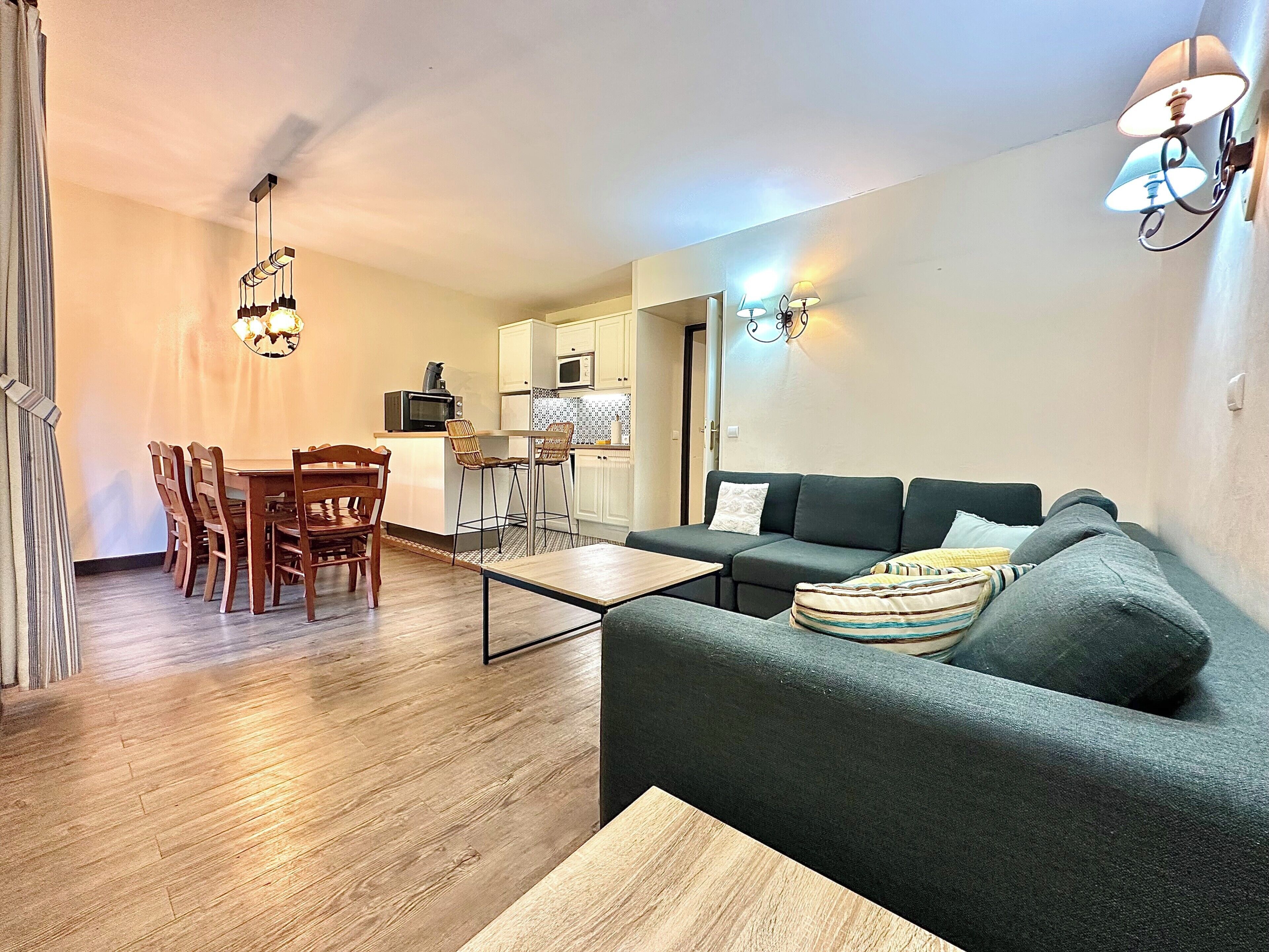 En kompakt opholdsstue med spiseplads, tekøkken og sofa.