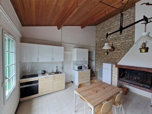 Eine moderne Küche mit weißen Schränken, Holzboden, Steinwand, Kamin und Essbereich mit Tisch und Stühlen.