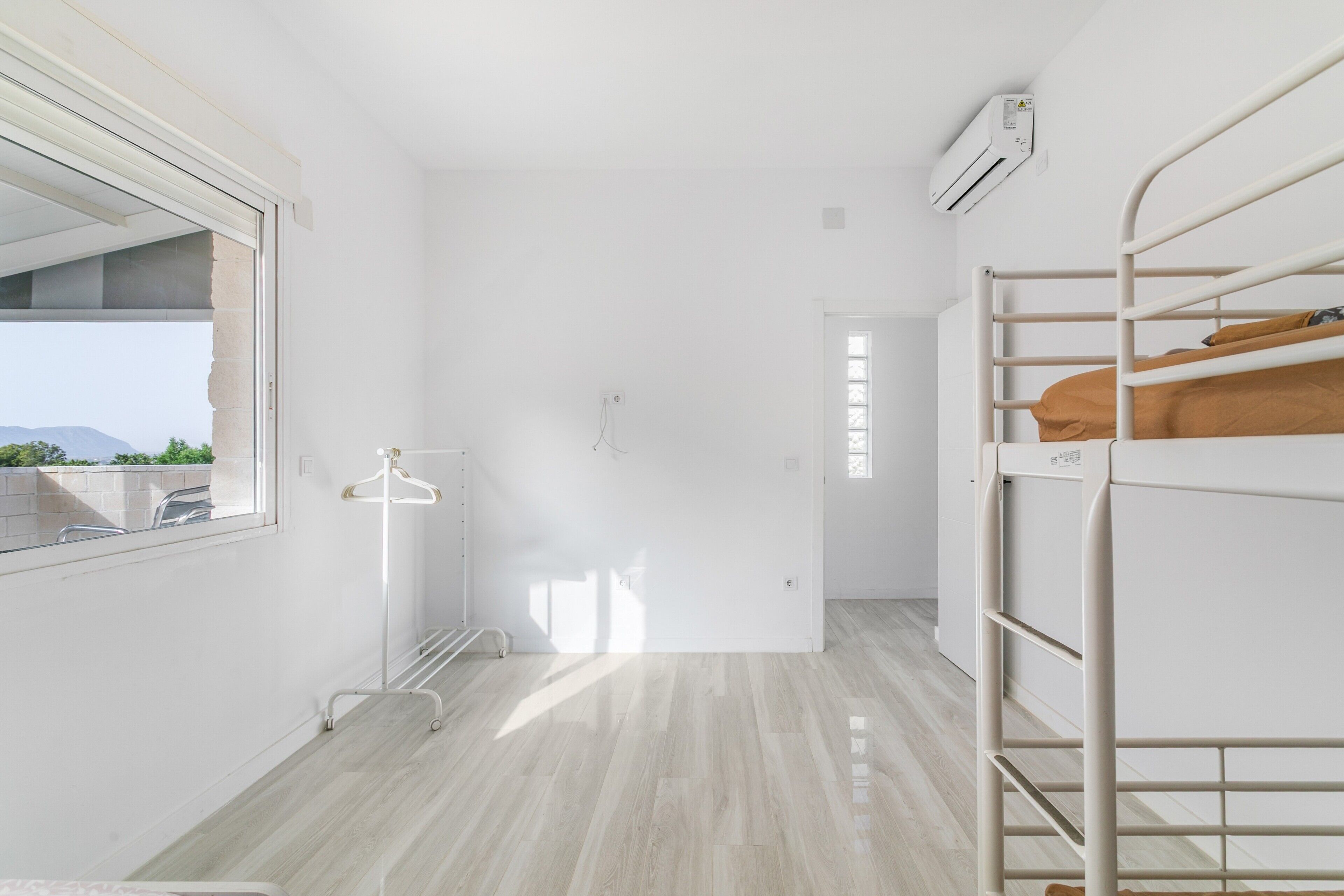 A minimalist room with bunk beds, a window, and an air conditioning unit.