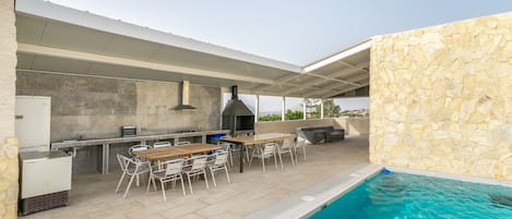An outdoor patio with a pool, a barbecue area, and a dining setup.