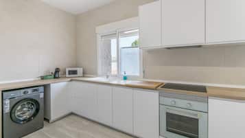 A modern kitchen with a washing machine, a microwave, a sink, and a built-in oven.