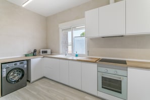 A modern kitchen with a washing machine, a microwave, a sink, and a built-in oven.