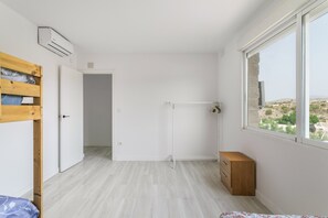 A minimalist room with a wooden bed, a small wooden dresser, and a large window offering a view of the landscape. - Villa 'Bender House' with Mountain View, Wi-Fi and Air Conditioning (Urbanización Villanueva)