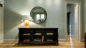En hall med ett svart konsolbord, en rund spegel och en lampa.