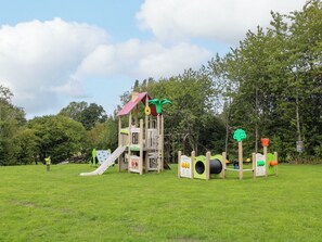 Un parque infantil con tobogán, estructuras de escalada y paneles lúdicos educativos.