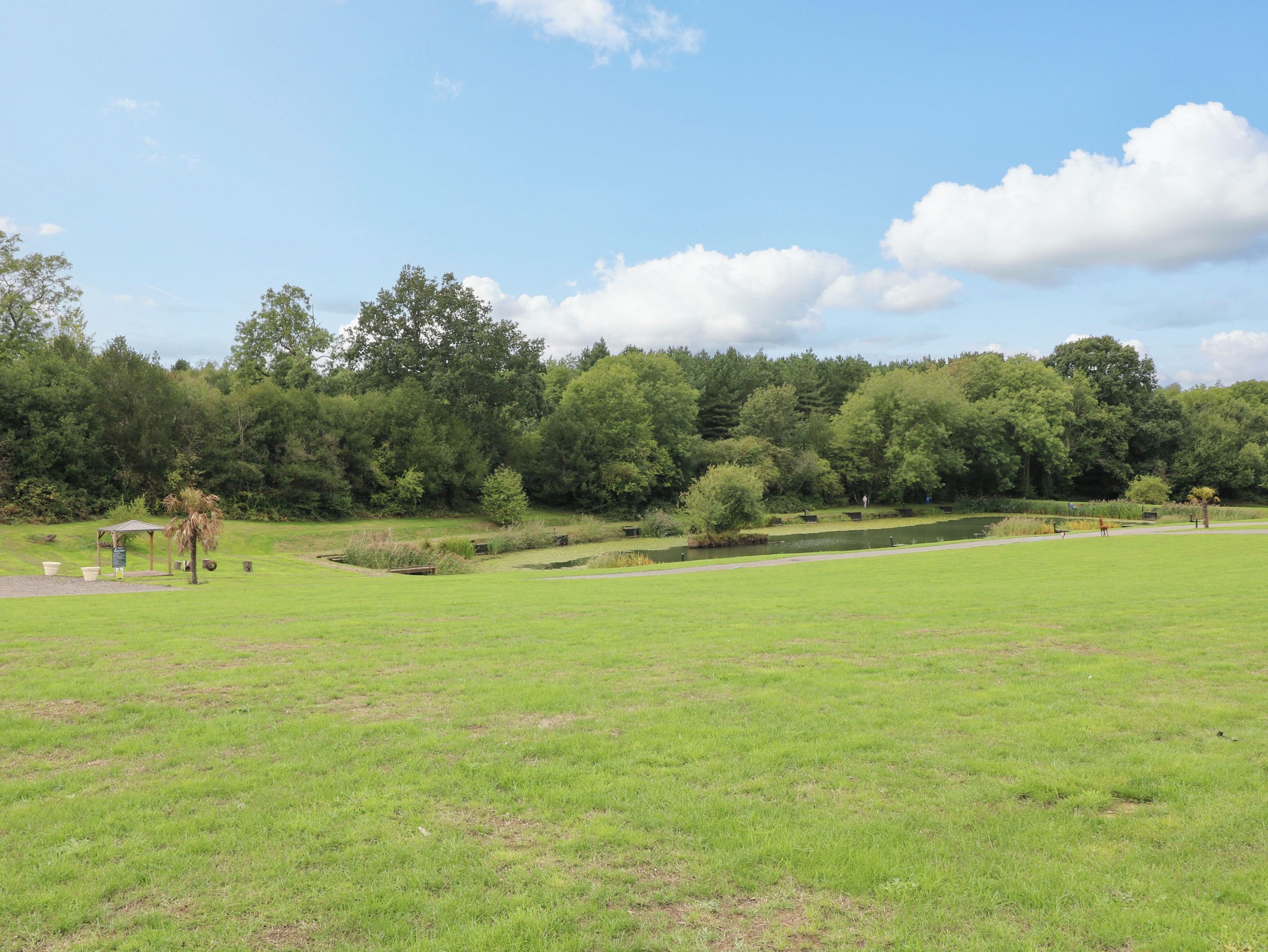 Ein Park mit Teich, Spazierwegen und einem Pavillon.