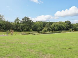 Un parque con un estanque, senderos peatonales y un quiosco.
