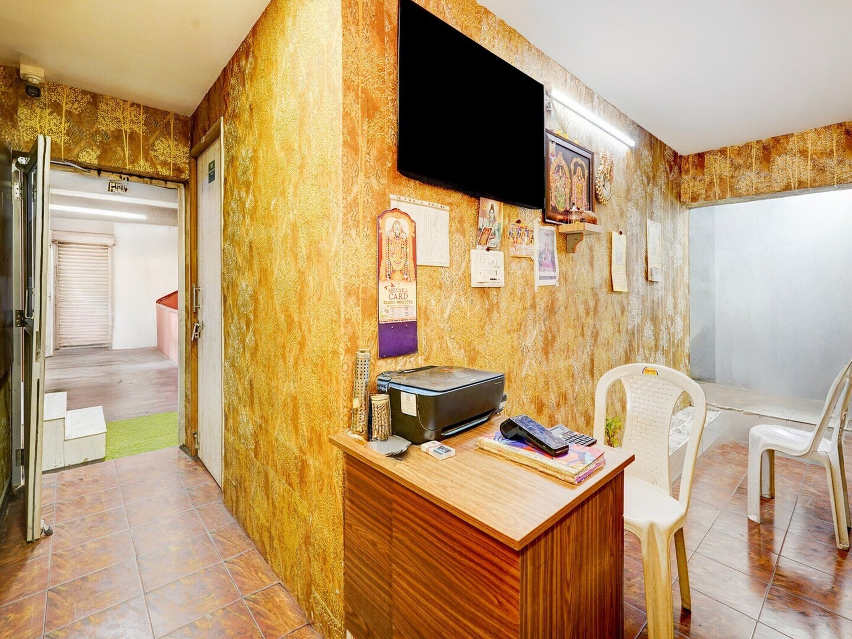 A room with a wooden desk, a television mounted on the wall, and a chair.