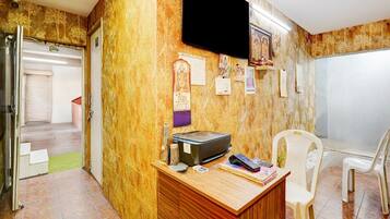 A room with a wooden desk, a television mounted on the wall, and a chair.