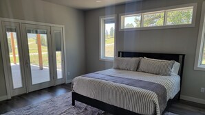 Une chambre à coucher avec un lit, une grande fenêtre et une porte-fenêtre coulissante.