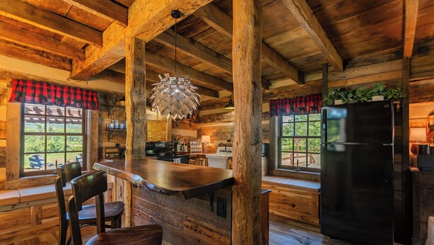 Eine rustikale Küche mit Holzbalken, einem schwarzen Kühlschrank und einer Bar mit Hockern.