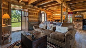 Ein rustikales Interieur mit Holzbalken, Ledersofas, einem Essbereich und Blick ins Freie.