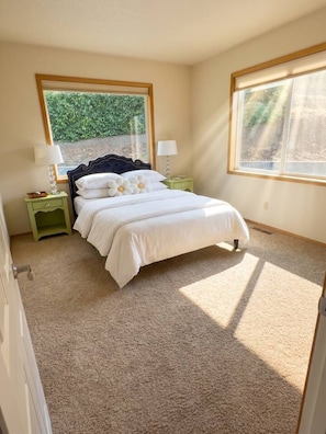 A bedroom with a bed, two nightstands, a window, and a door.