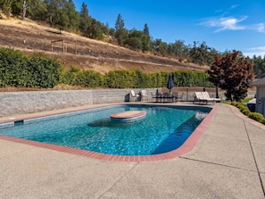 A rectangular swimming pool with a hot tub in the center, surrounded by a brick border.