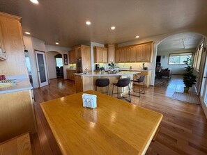 A spacious kitchen with wooden cabinets, a central island with seating, and a dining table.