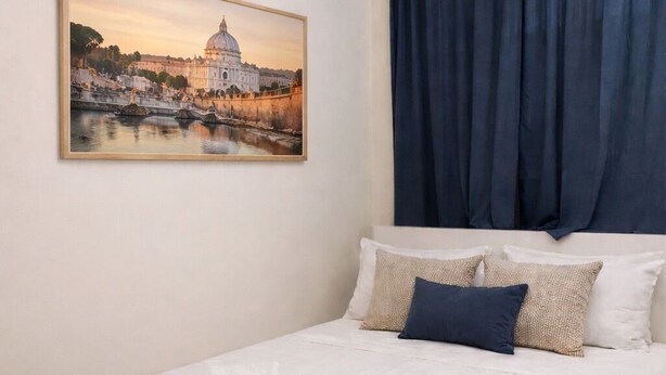 Een hotelkamer met een bed, een stadsgezicht op canvas, een raam met gordijnen en een witte sprei.