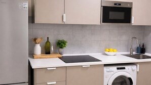 Een keuken met een koelkast, magnetron, spoelbak en wasmachine.
