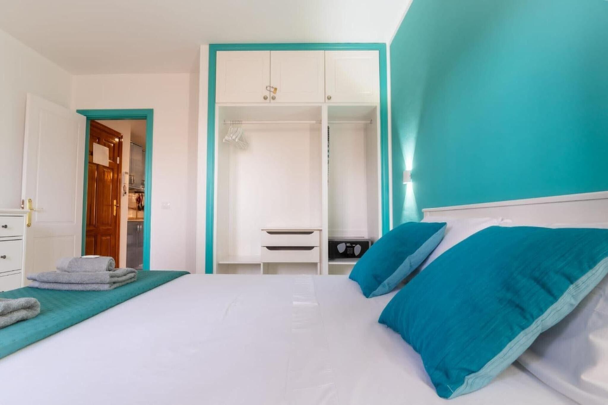 A bedroom with a bed, a wardrobe, and a bathroom visible through an open door.