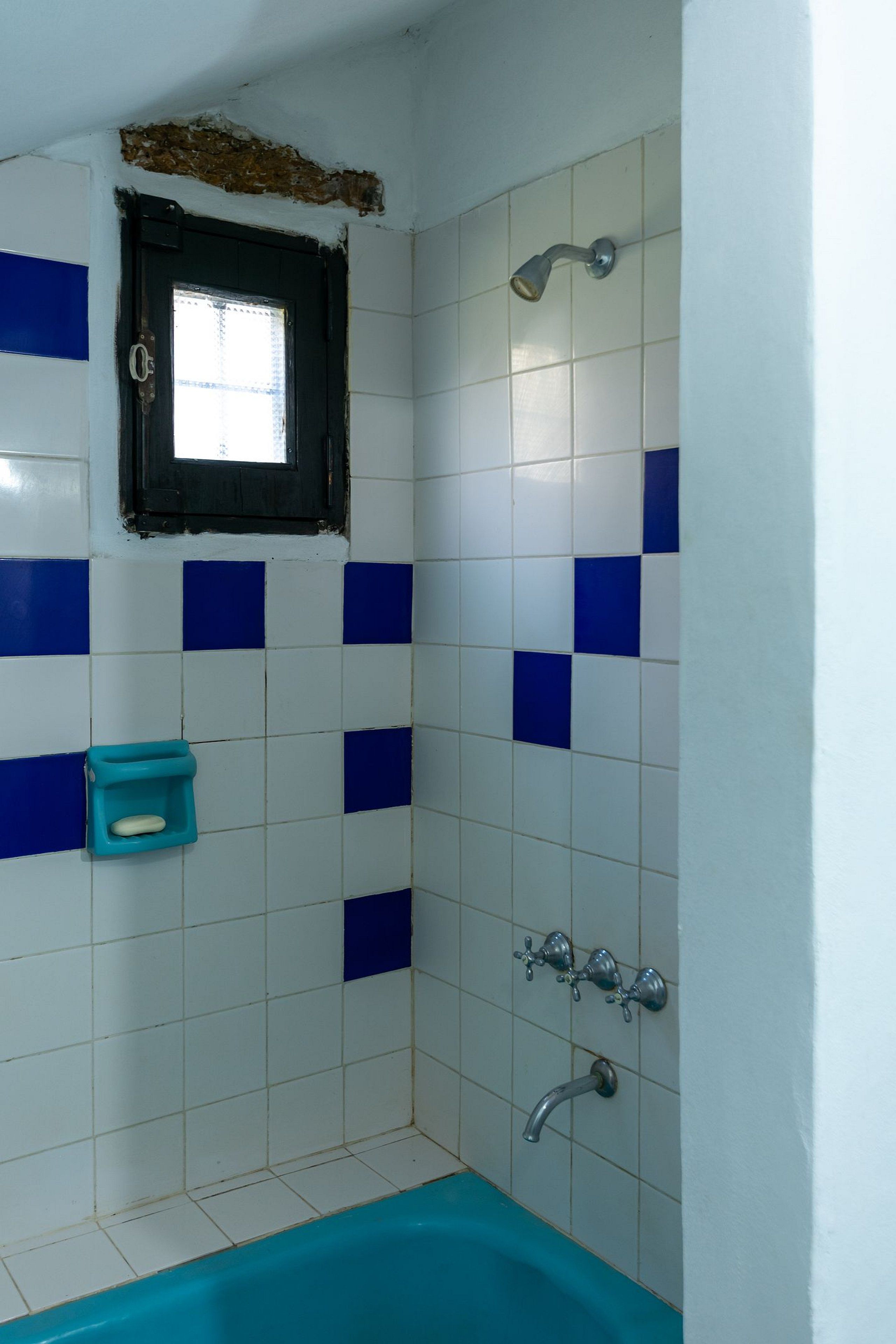 A bathroom with a bathtub, a window, and a shower.