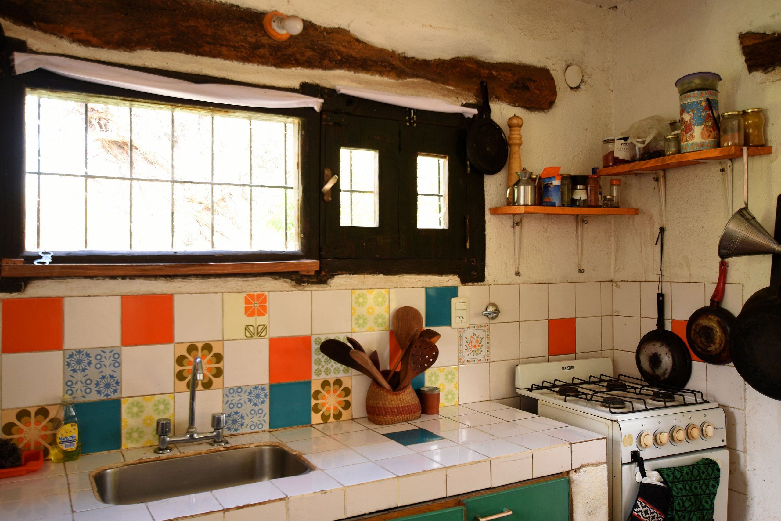 A kitchen with a gas stove, a sink, and a window with curtains.