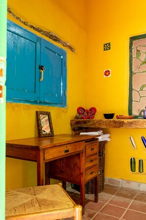 Una habitación con un escritorio de madera, una silla, un armario azul y suelo de baldosas.