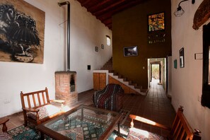 Une pièce avec une cheminée, une table en verre, des tapis à motifs et un escalier menant à un autre niveau.