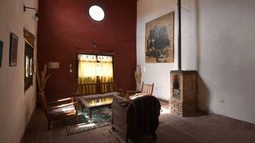A room with a red wall, a wooden bench, a table, a patterned rug, a fireplace, and a painting.
