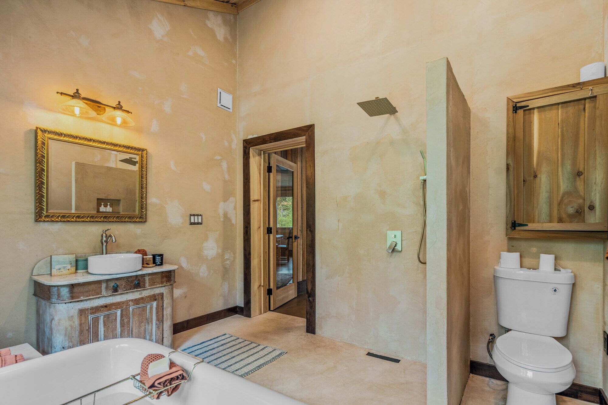 Une salle de bain équipée d’une baignoire, d’un lavabo, d’un miroir et de toilettes.